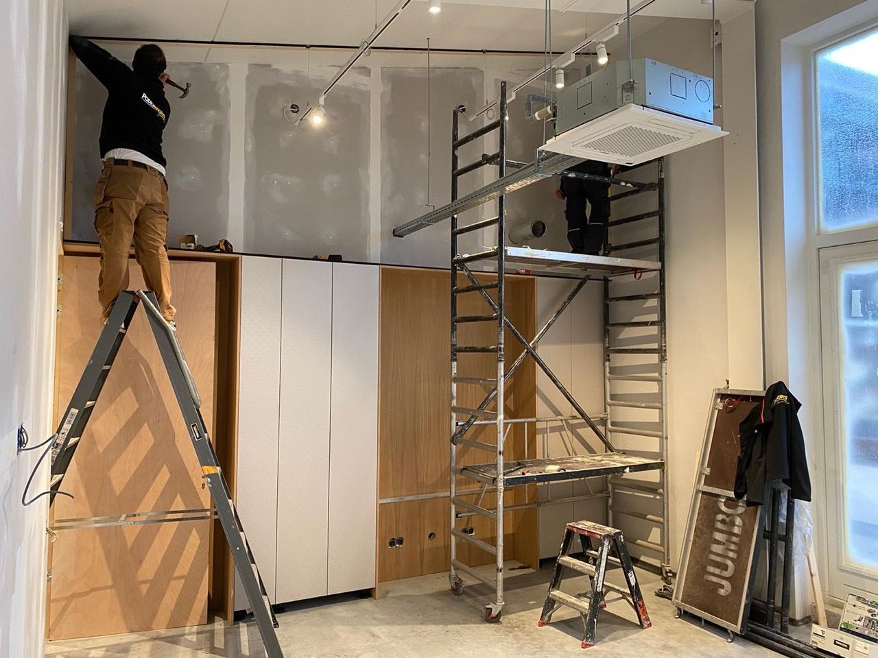 Een man staat op een ladder in een kamer.