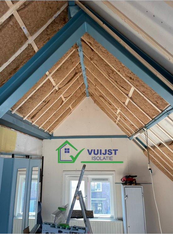 Glaswolisolatie zorgvuldig aangebracht in de zoldermuur, gezien van binnenuit. De foto toont de dikke laag glaswol die tussen de houten stijlen van de muur is geplaatst, waardoor een effectieve barrière tegen warmteverlies wordt gecreëerd. De textuur van de glaswol is goed zichtbaar, wat de kwaliteit en de dichtheid van het isolatiemateriaal benadrukt, essentieel voor het verhogen van de energie-efficiëntie en het comfort van de woning.