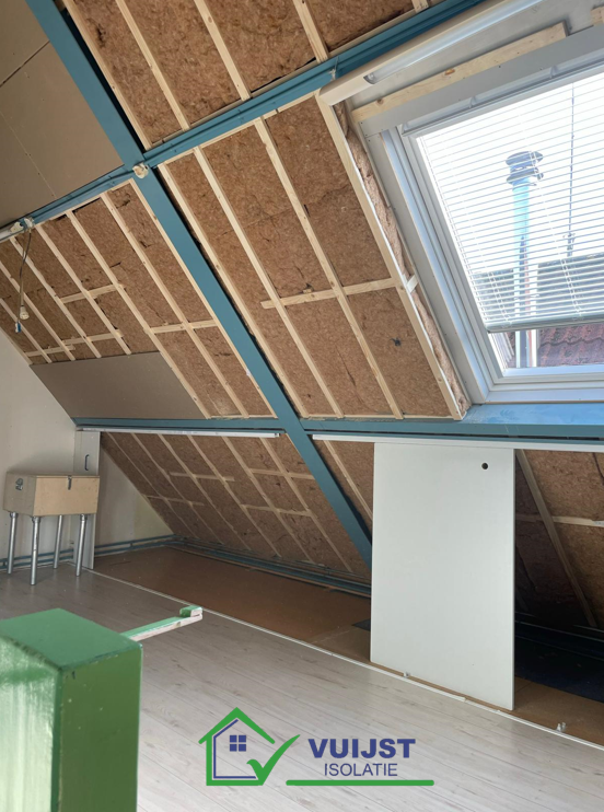 Glaswolisolatie zorgvuldig aangebracht in de zoldermuur, gezien van binnenuit. De foto toont de dikke laag glaswol die tussen de houten stijlen van de muur is geplaatst, waardoor een effectieve barrière tegen warmteverlies wordt gecreëerd. De textuur van de glaswol is goed zichtbaar, wat de kwaliteit en de dichtheid van het isolatiemateriaal benadrukt, essentieel voor het verhogen van de energie-efficiëntie en het comfort van de woning.