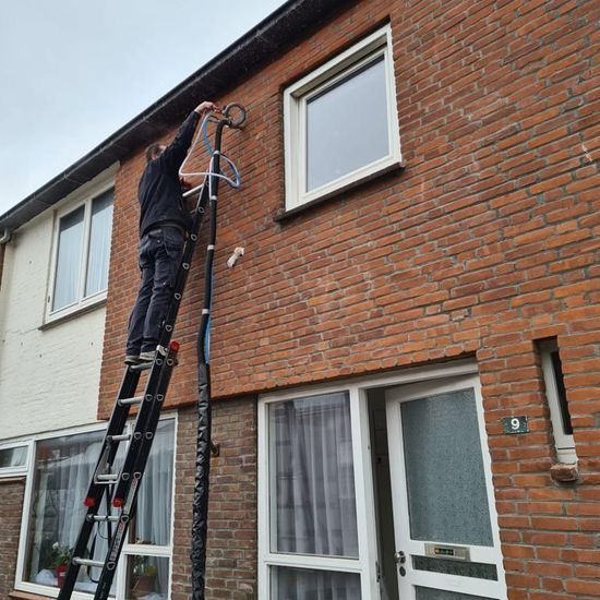Theo Vuijst, expert in isolatie en eigenaar van Vuijst Renovatie & Verduurzaming, past zorgvuldig spouwmuurisolatie toe in een muur. De foto toont hem terwijl hij isolatiemateriaal injecteert in de spouw van een woning, een techniek die bijdraagt aan het verhogen van de energie-efficiëntie en het comfort van het huis.