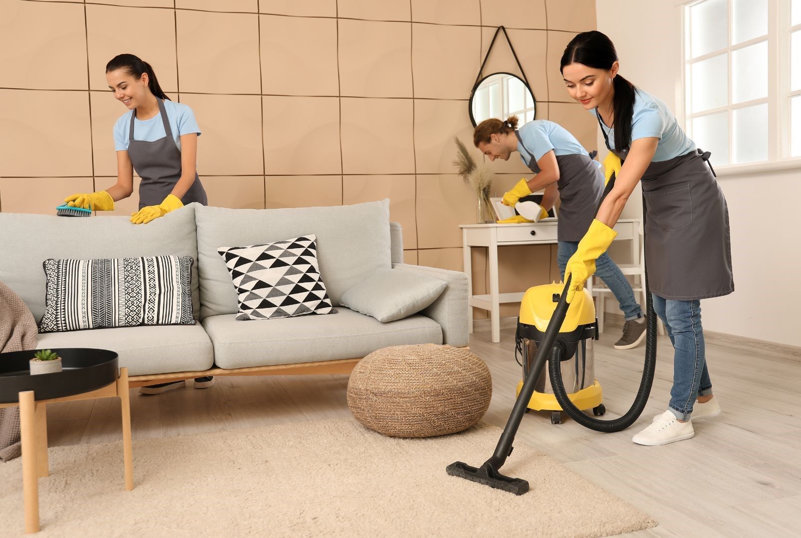 Three women are cleaning a living room with a vacuum cleaner.