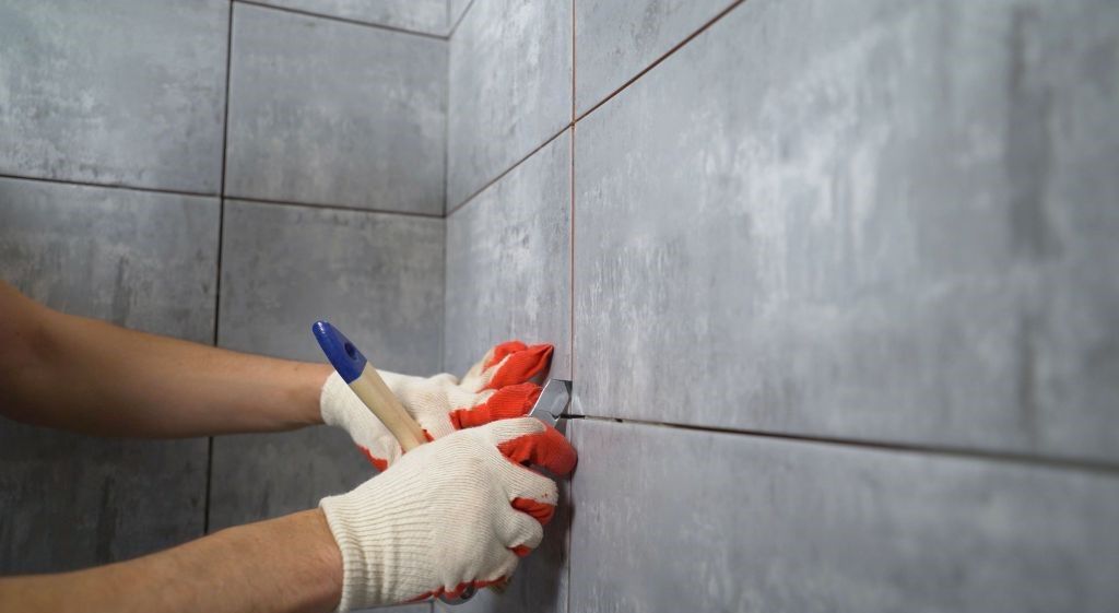 A man is measuring a tile wall with a tape measure.