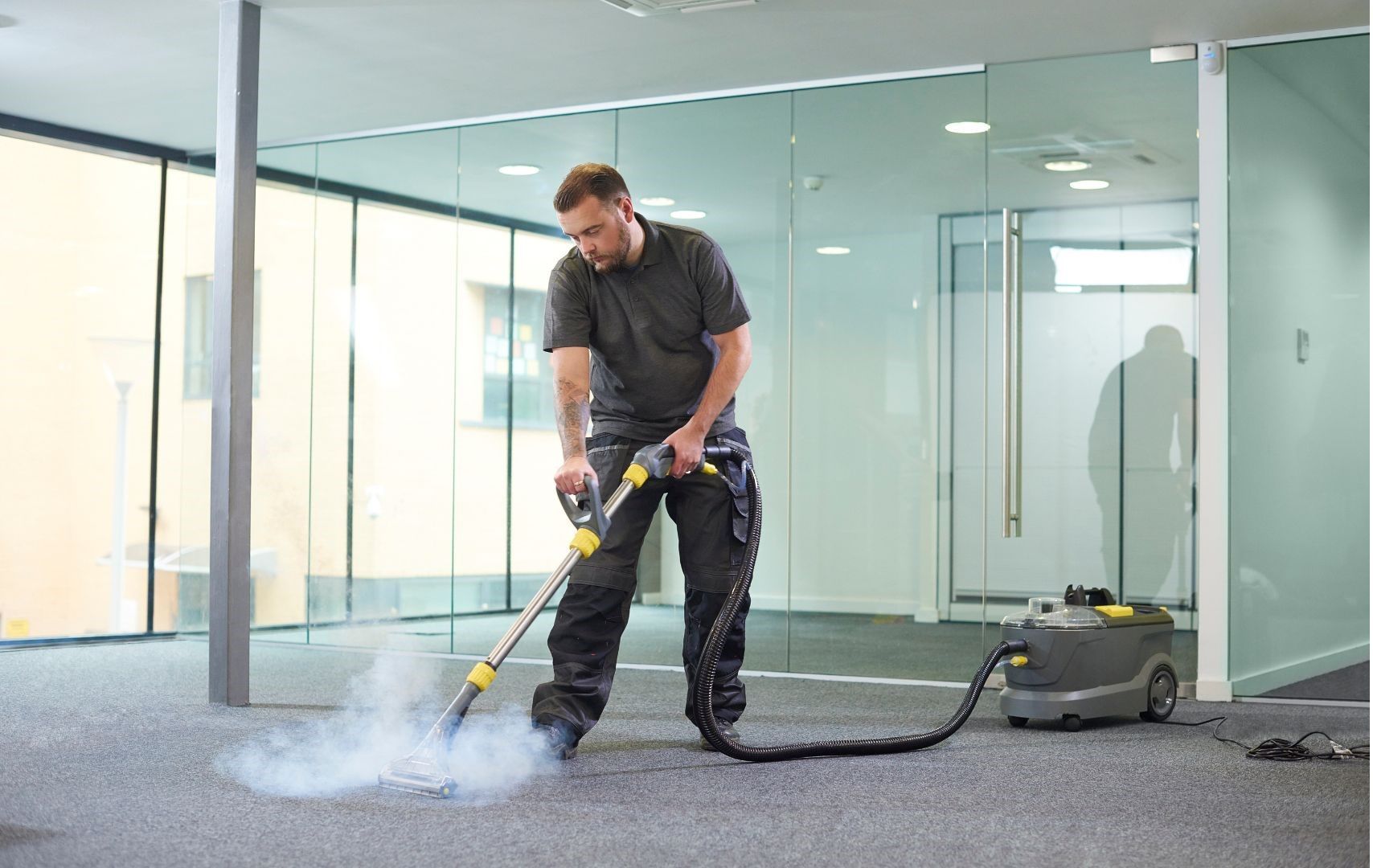 A man is cleaning the floor with a vacuum cleaner.