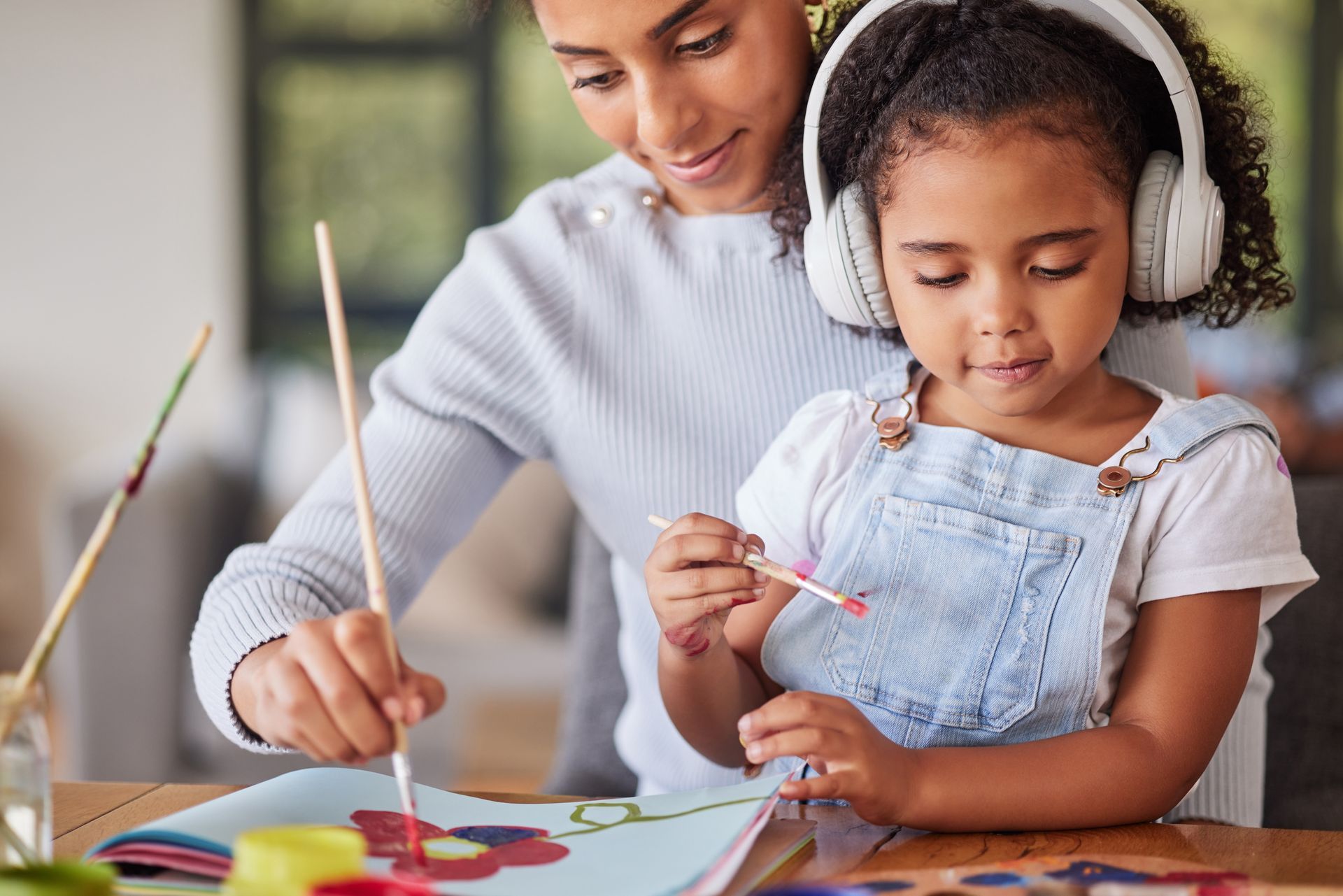 A woman and a little girl are painting a picture together.