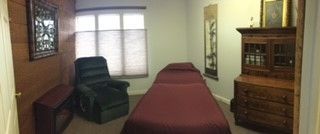 A room with a bed, chair, dresser and window