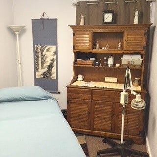 A room with a bed, dresser, lamp and clock on the wall