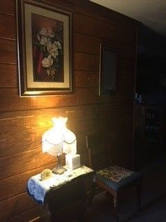 A lamp is sitting on a table next to a chair in a dark room