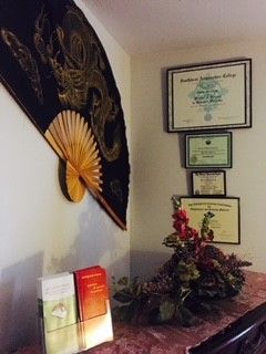 A room with a fan hanging on the wall and flowers on the table