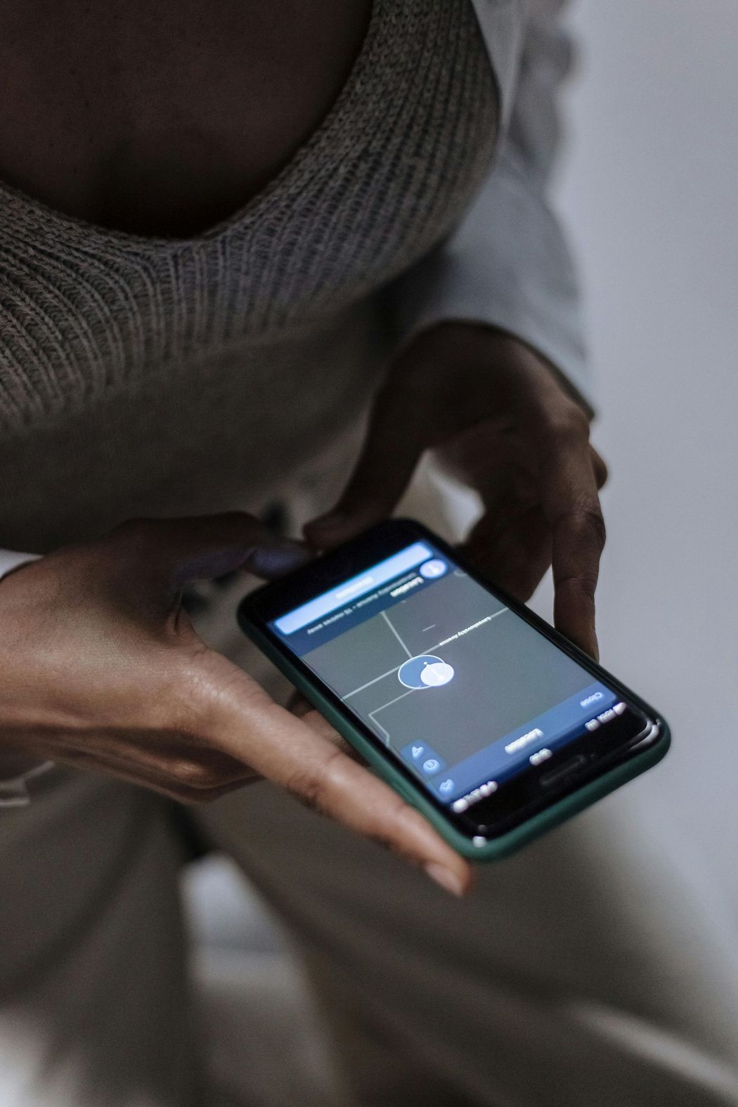 Person holding a smartphone displaying an app with a white dot on a blue background.