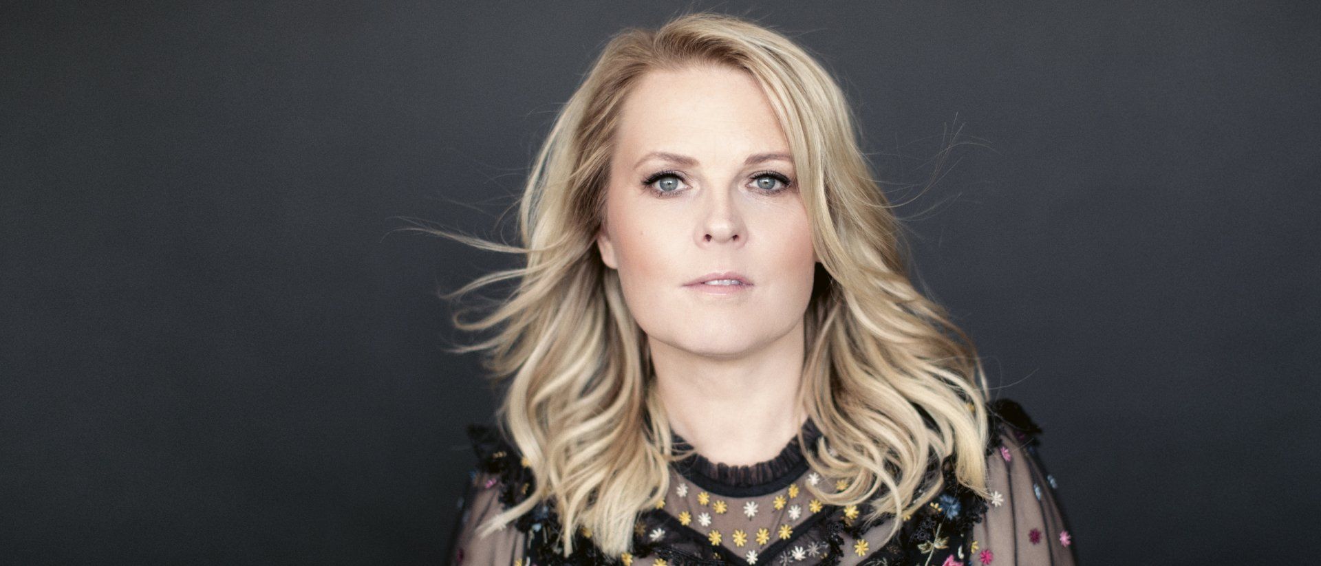 Eine Frau mit einer Blume im Haar trägt ein rosa Kleid