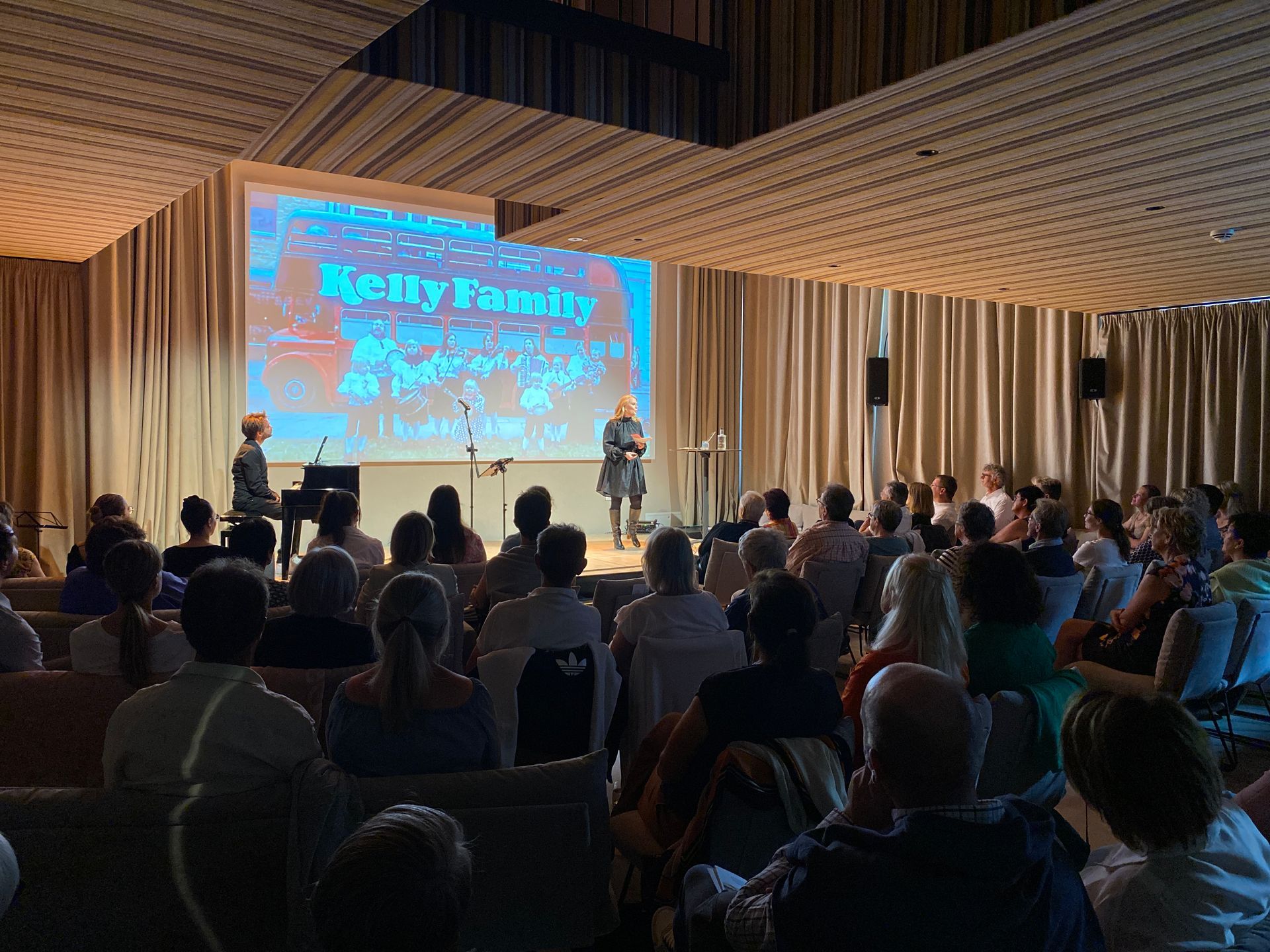 Eine Frau hält in einem großen Auditorium vor einer großen Gruppe von Menschen einen Vortrag.
