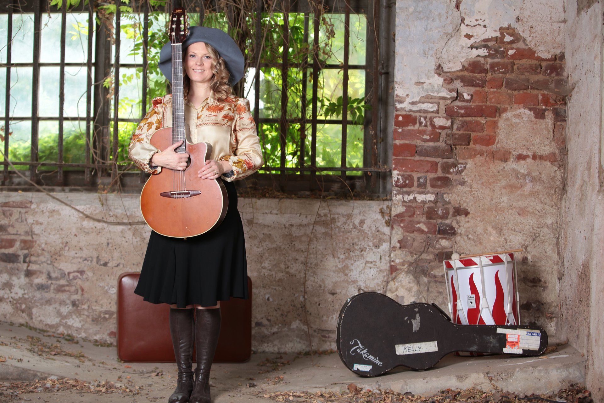 Eine Frau mit einer Gitarre vor einer Backsteinmauer