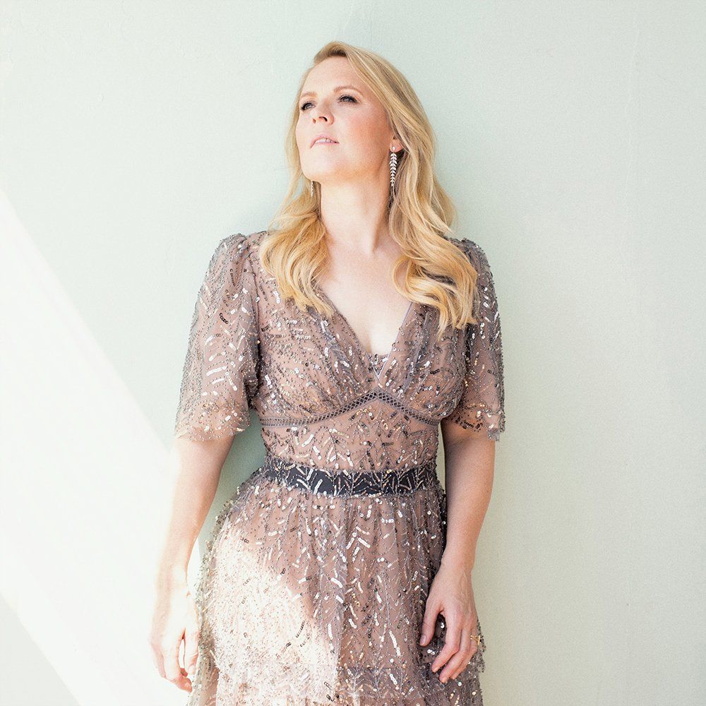 Eine Frau in einem Kleid steht vor einem Fenster.