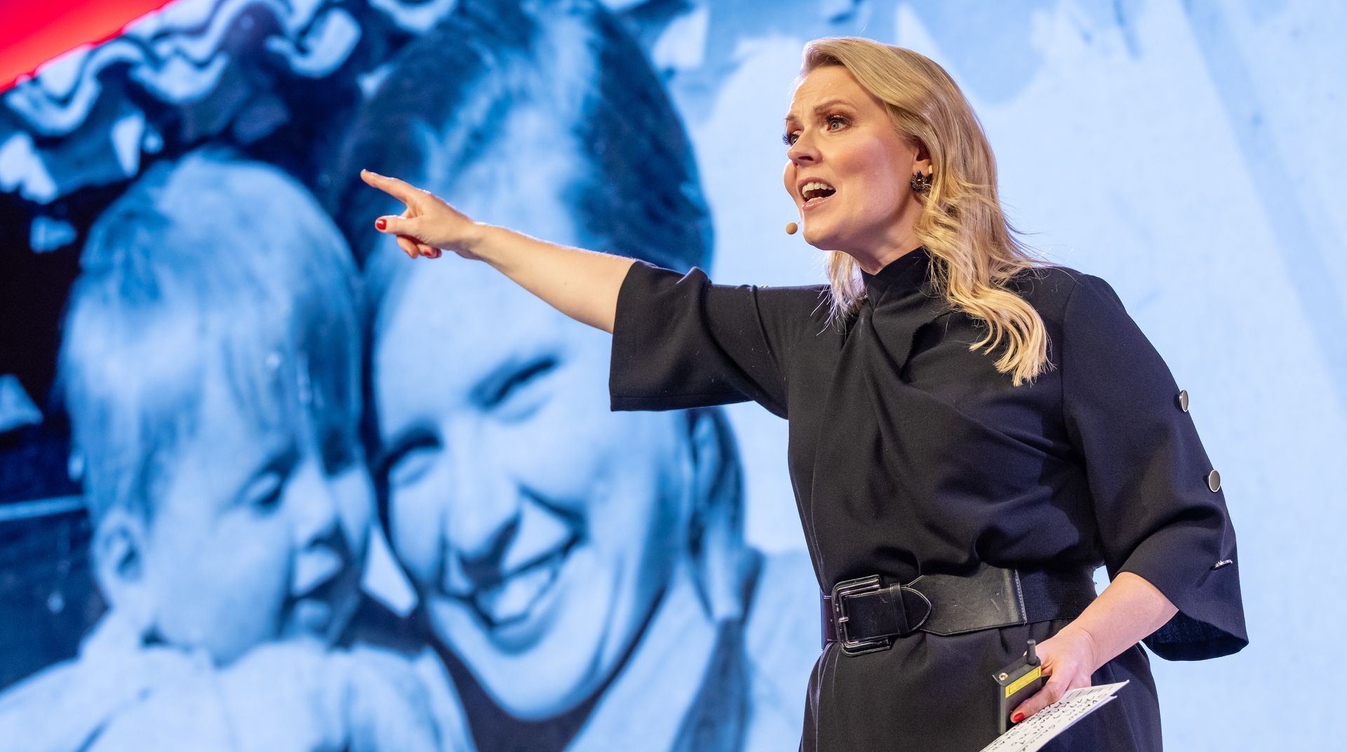 Eine Frau steht auf einer Bühne vor einer Menschenmenge.