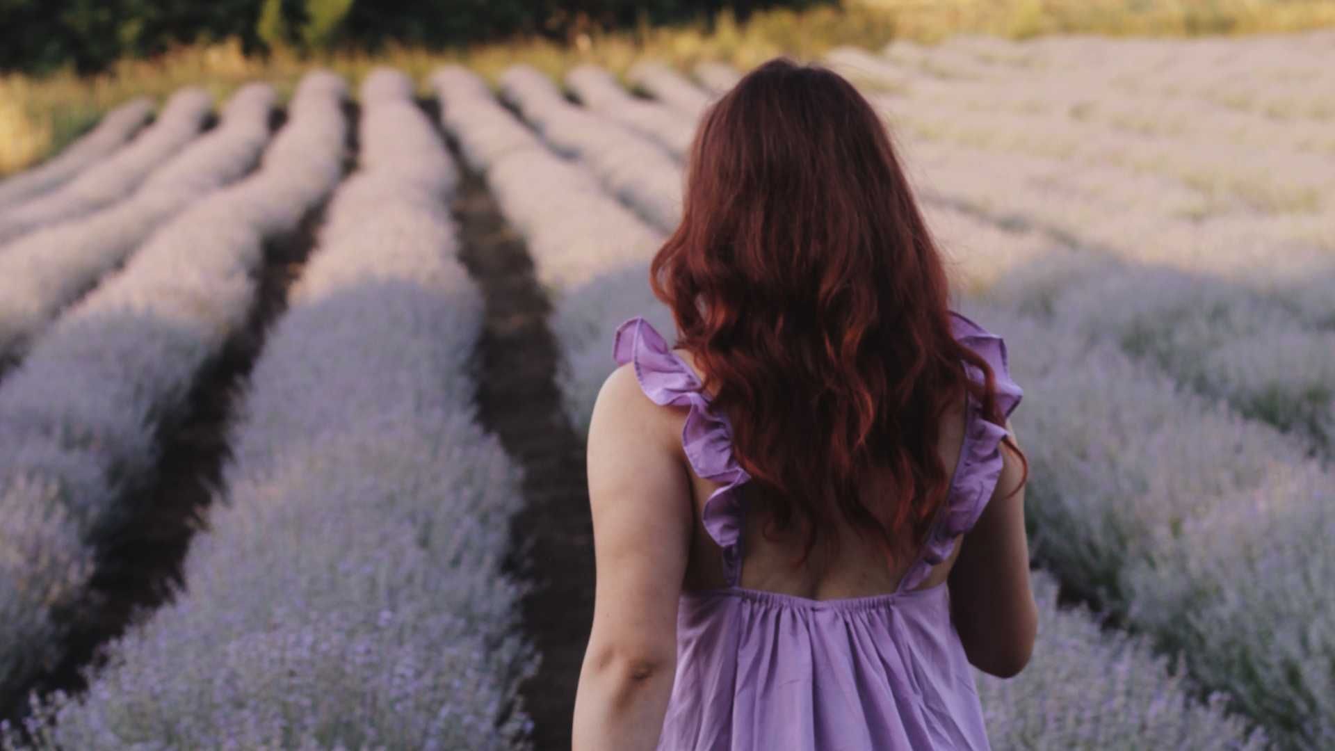 A woman in a purple dress is standing in a lavender field.