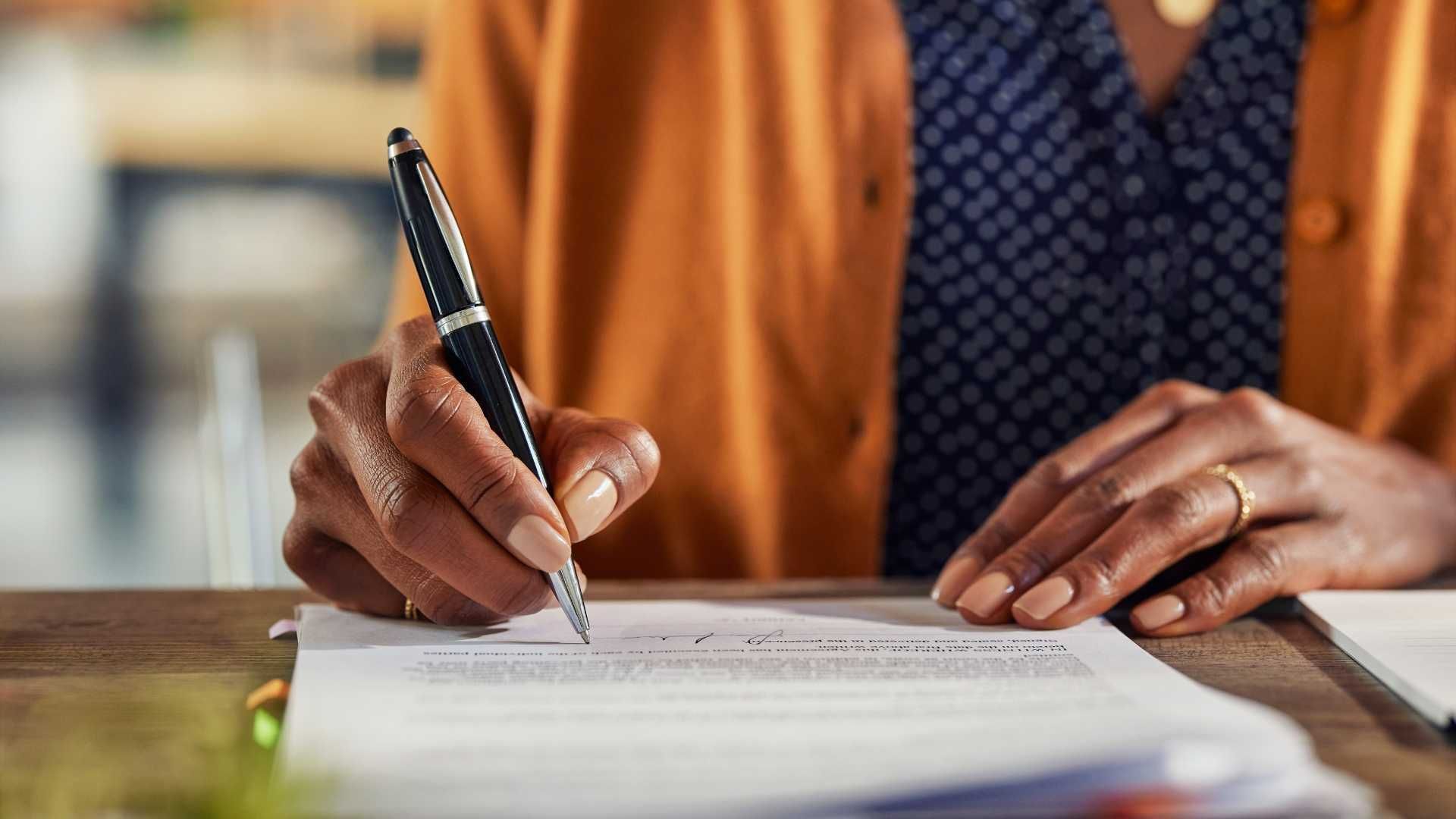 A woman is writing on a piece of paper with a pen.