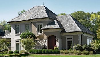 a large house with a slate roof is sitting on top of a lush green lawn .