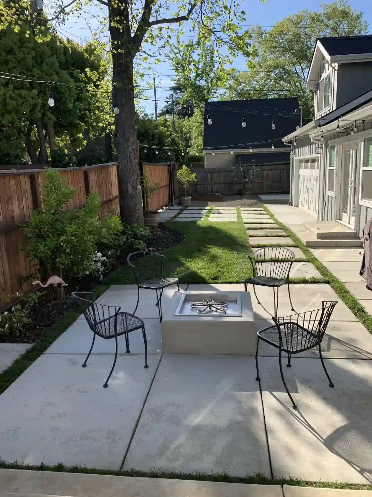 A patio with chairs and a fire pit in the backyard of a house.