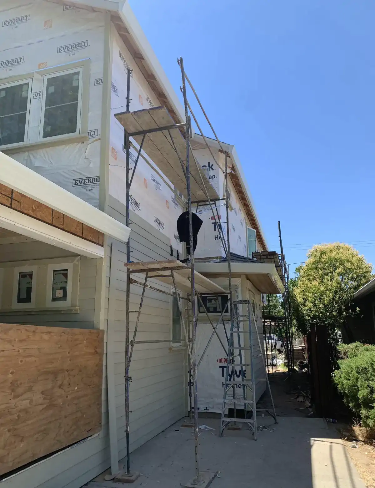 A man is standing on a scaffolding on the side of a house.