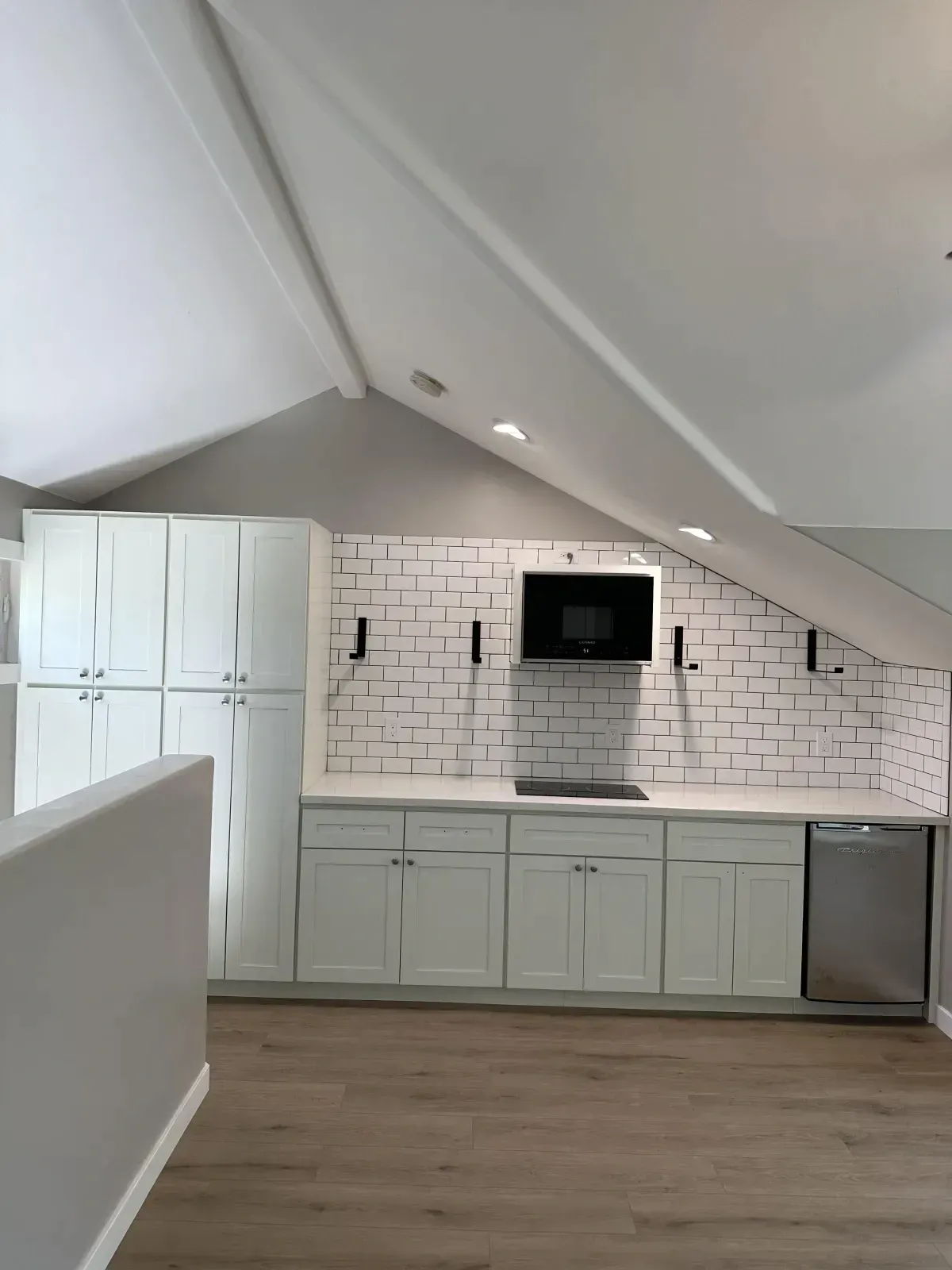 A kitchen with white cabinets and a brick wall.
