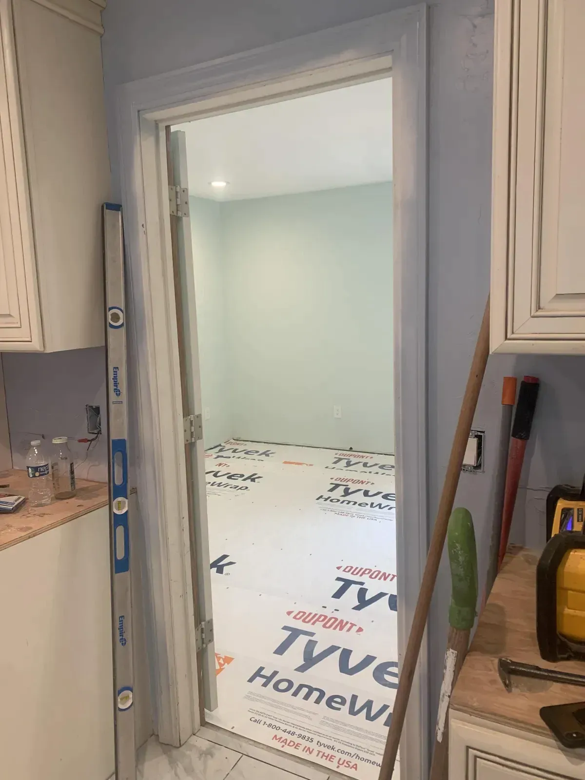 A kitchen with a door that is open and a mop on the counter.