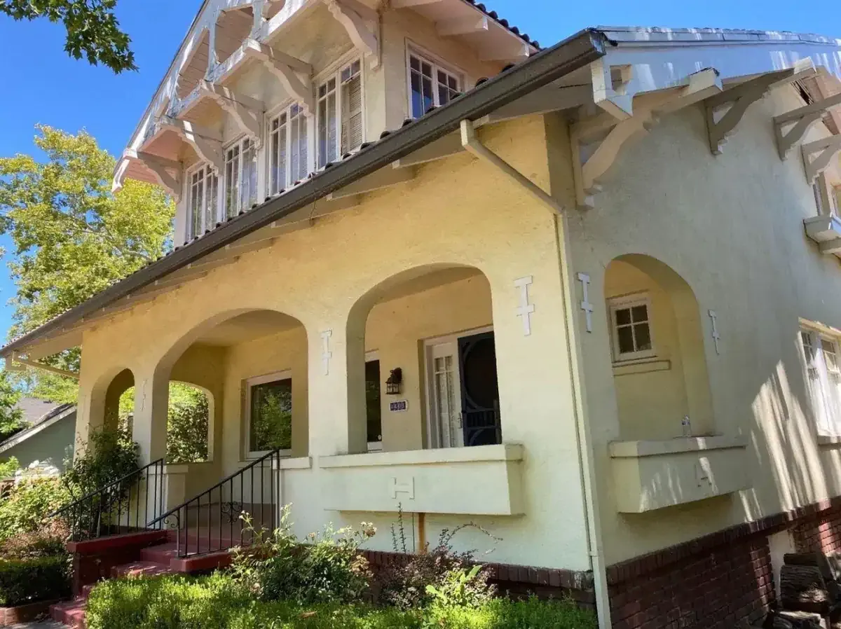 A large white house with arched porch and stairs