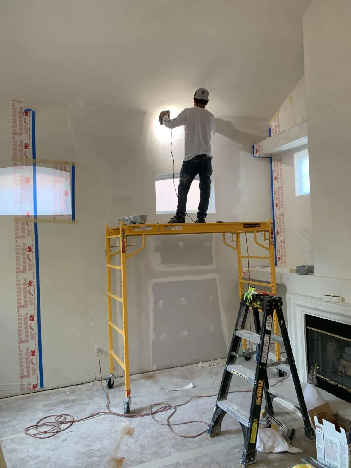 A man is standing on top of a scaffolding in a living room.