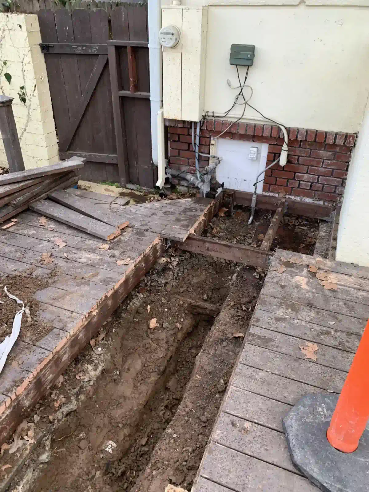 A wooden deck is being demolished in front of a brick wall.