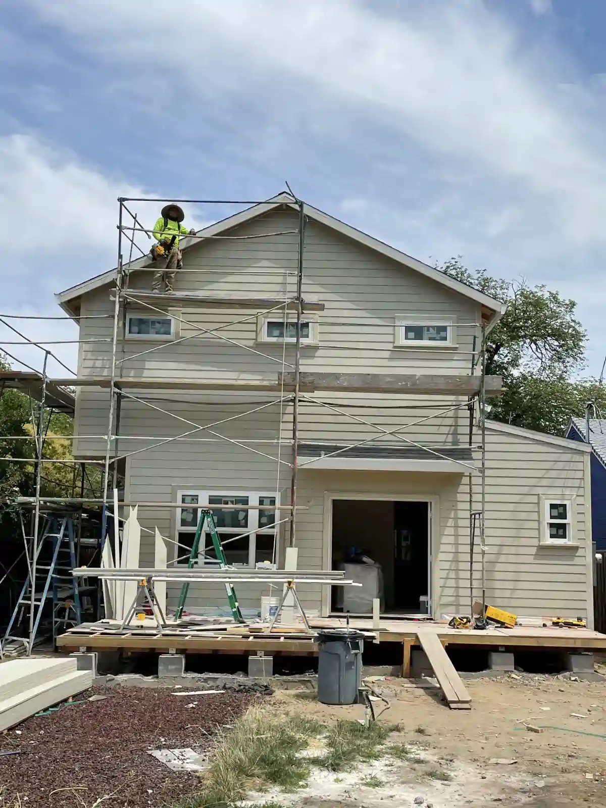 A man is sitting on a scaffolding on the side of a house.
