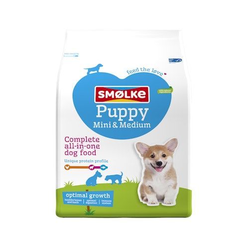 Een zak Smølke Puppy Mini & Medium hondenvoer met een afbeelding van een puppy op een grasachtergrond.