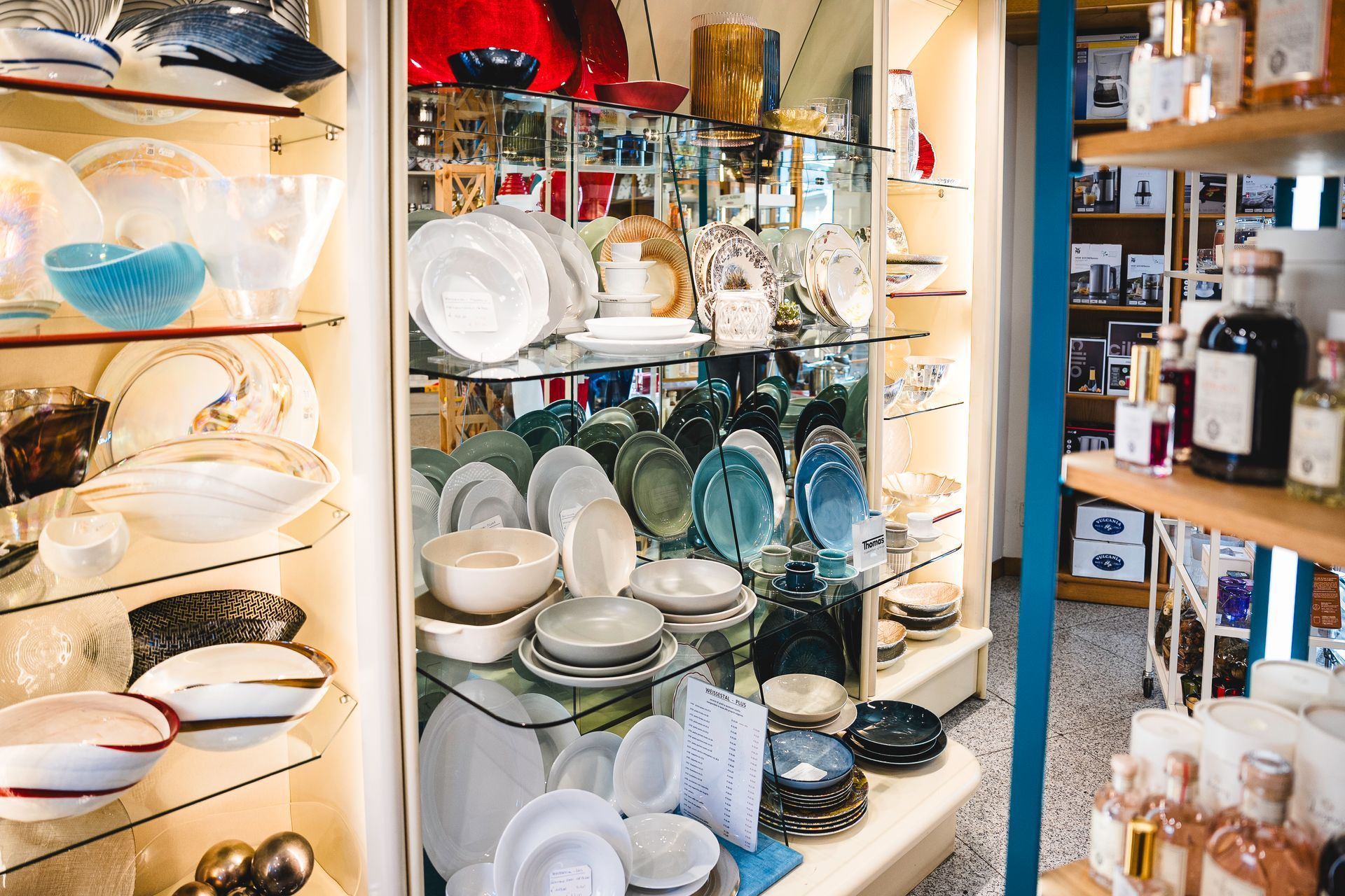 Uno scaffale espositivo in negozio che presenta una varietà di ciotole, piatti e flaconi