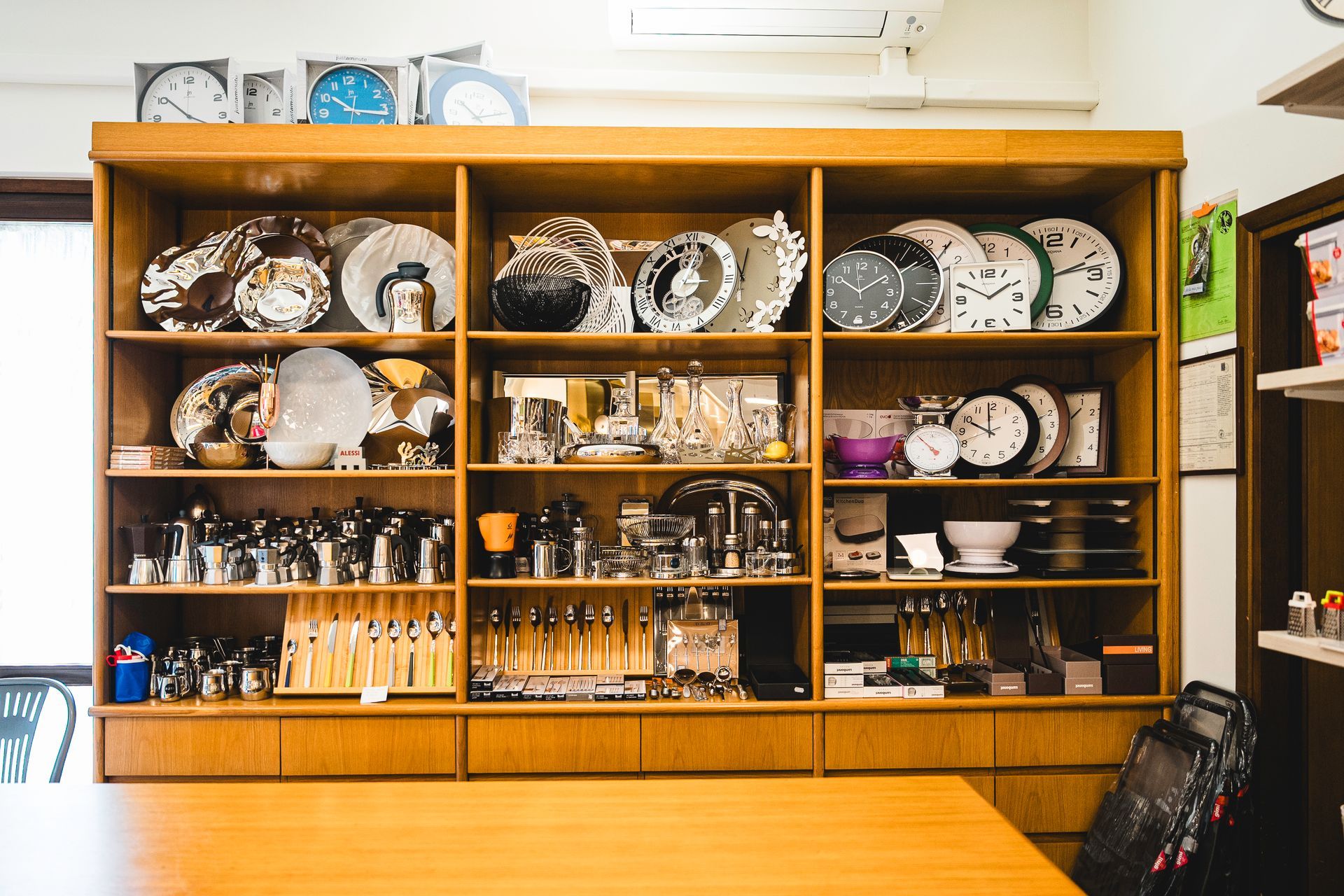 Una grande vetrina in legno piena di orologi, piatti e utensili da cucina.