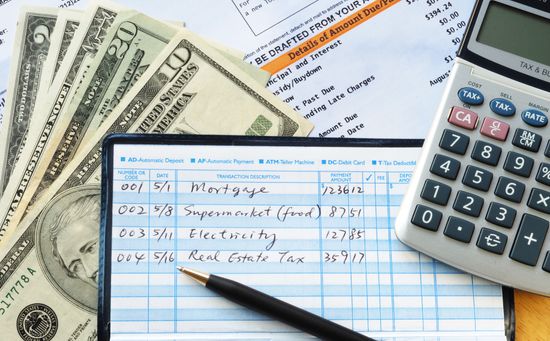 money, calculator, and checkbook on table