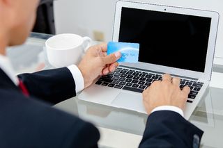 man paying bills online with card in hand