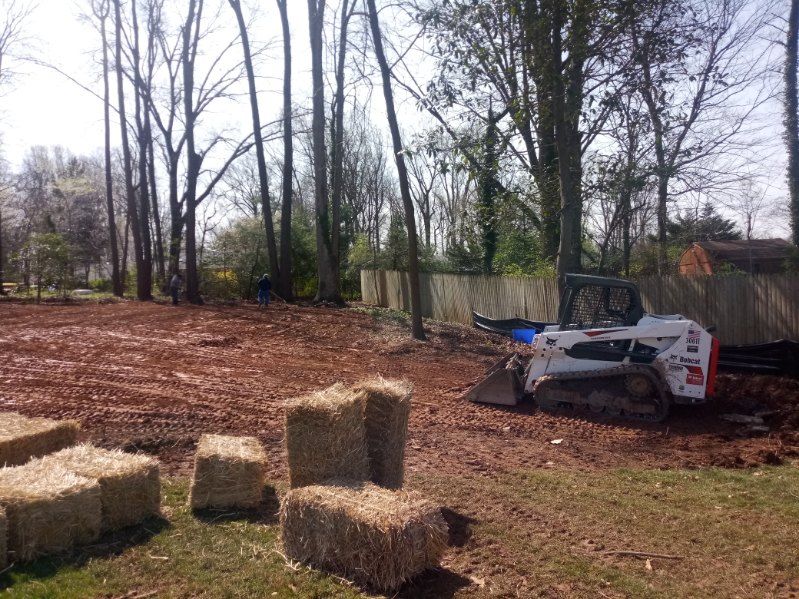 A bulldozer is moving hay bales in a field.