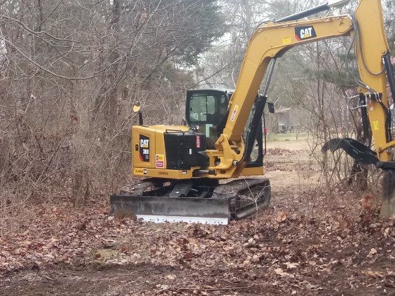 A cat excavator is digging in the dirt in a field.