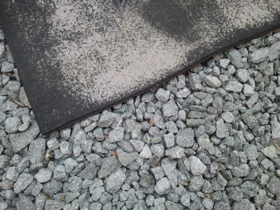 A pile of gravel next to a piece of metal.