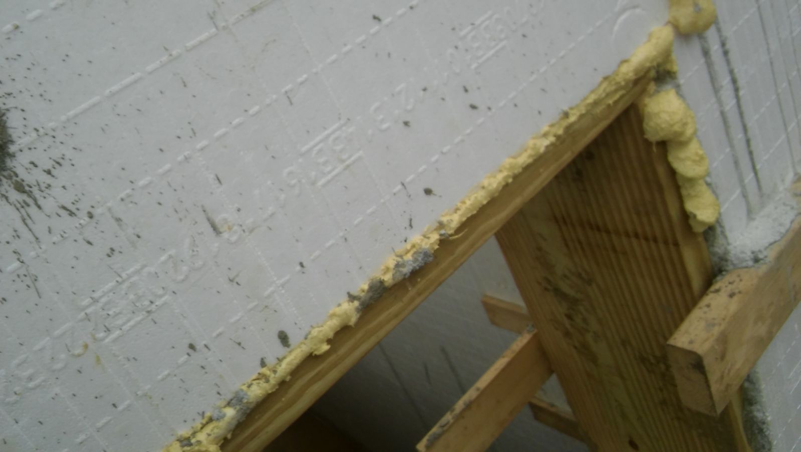 A close up of a brick wall with foam on it and a wooden frame.