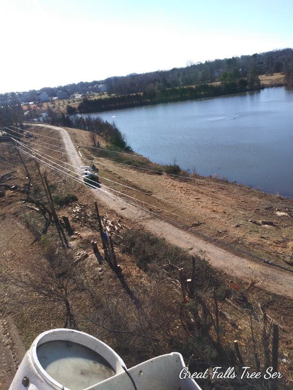 A large white bucket is sitting on top of a dirt road next to a lake.