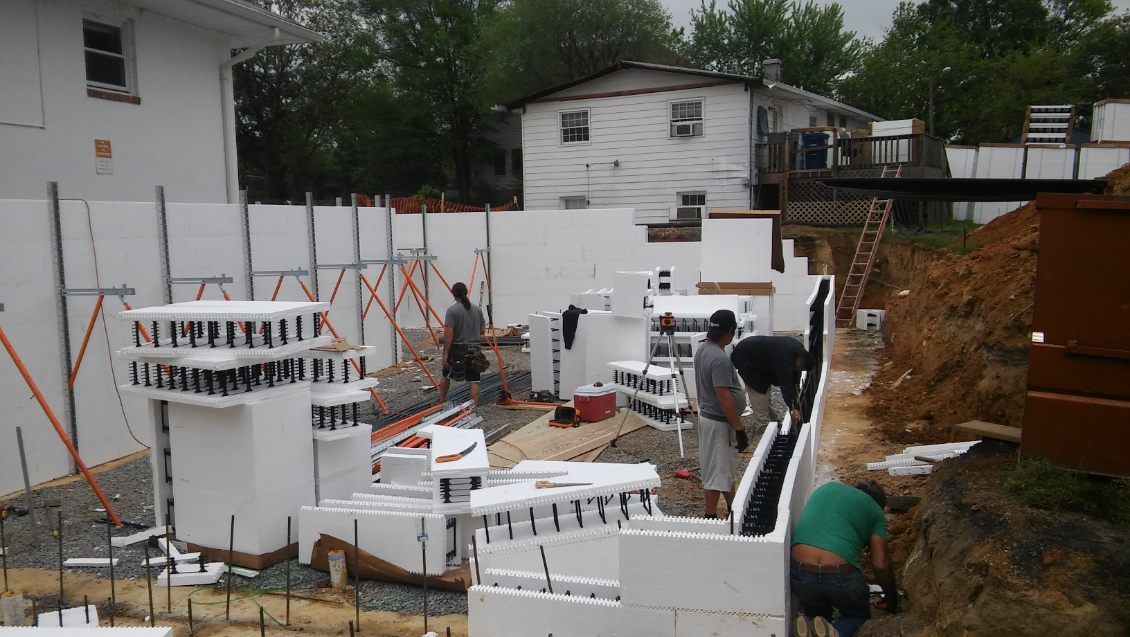 A group of people are working on a construction site in front of a house.