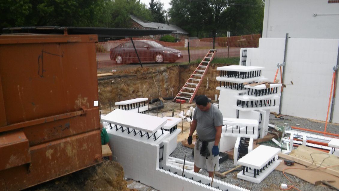 A man is standing in front of a pile of styrofoam blocks.