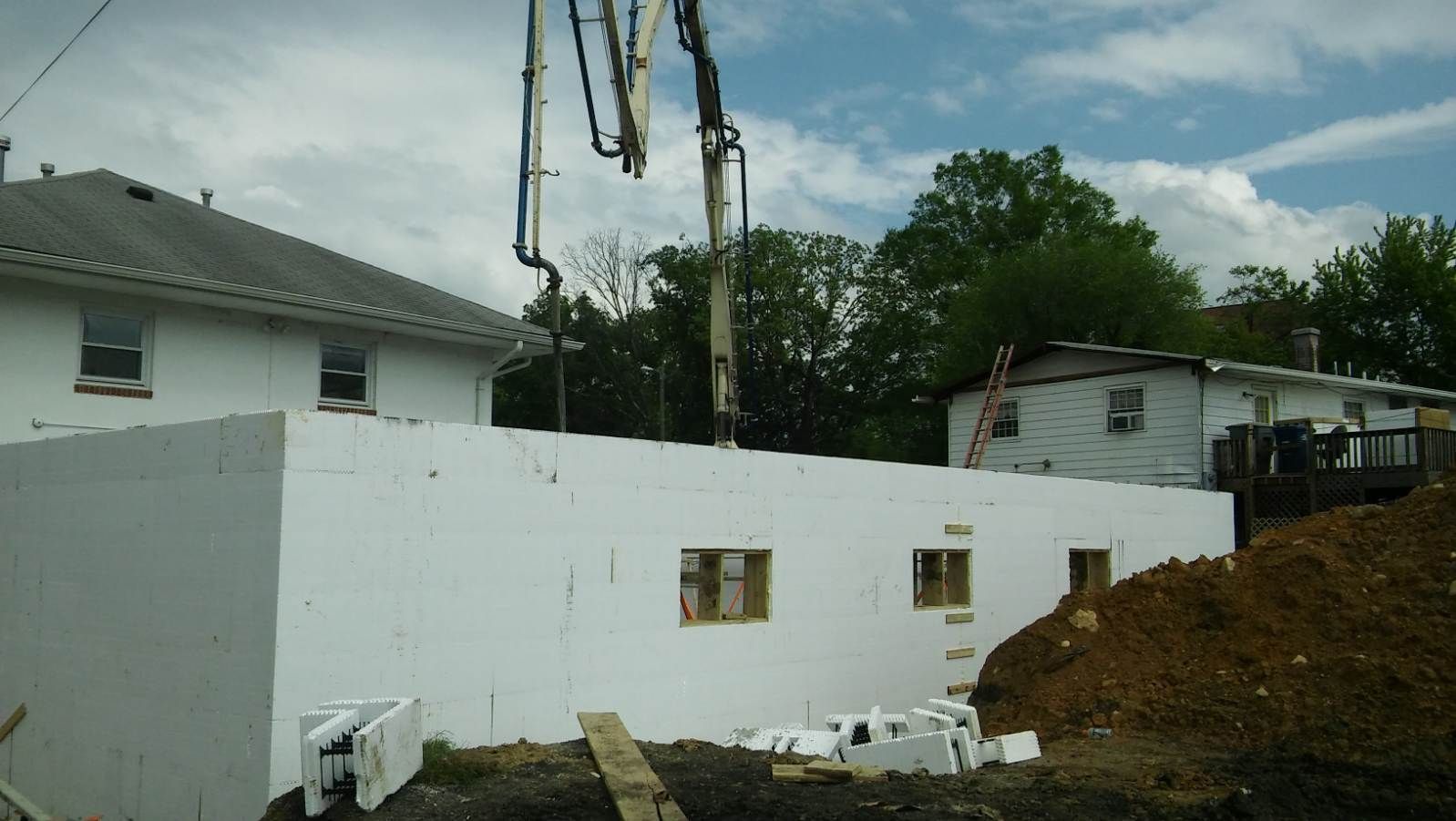A concrete pump is being used to pour concrete into a house