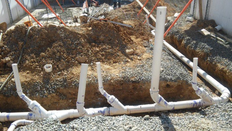 A bunch of white pipes are laying in the dirt