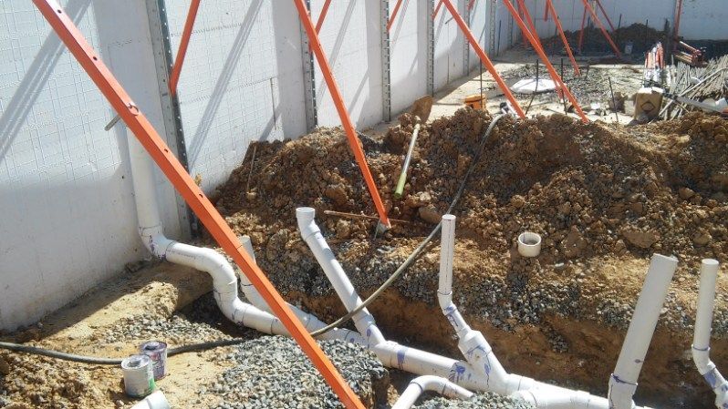 A bunch of pipes are laying in the dirt