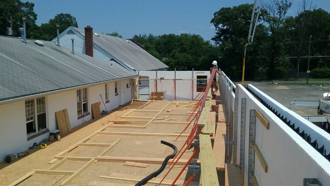 A man is standing on a wooden platform in front of a building under construction.