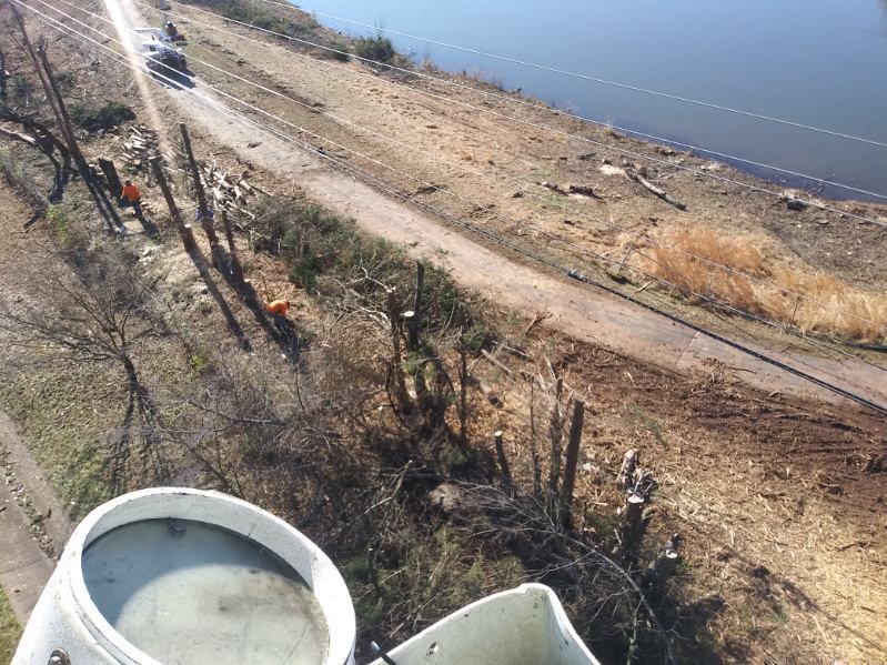 A couple of barrels are sitting on the side of a road next to a body of water.