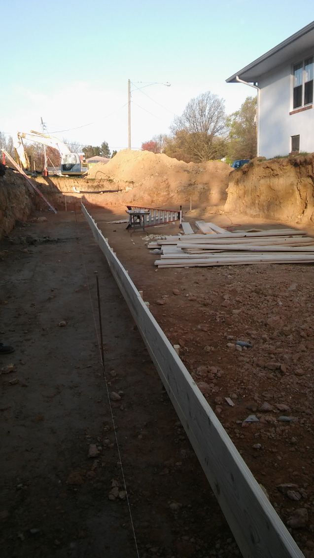 A dirt road leading to a house under construction.