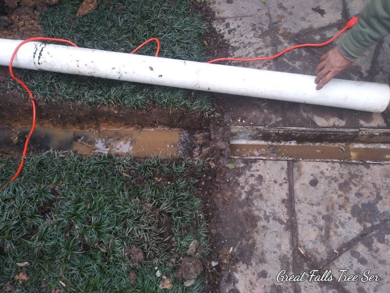 A person is laying a white pipe on the ground