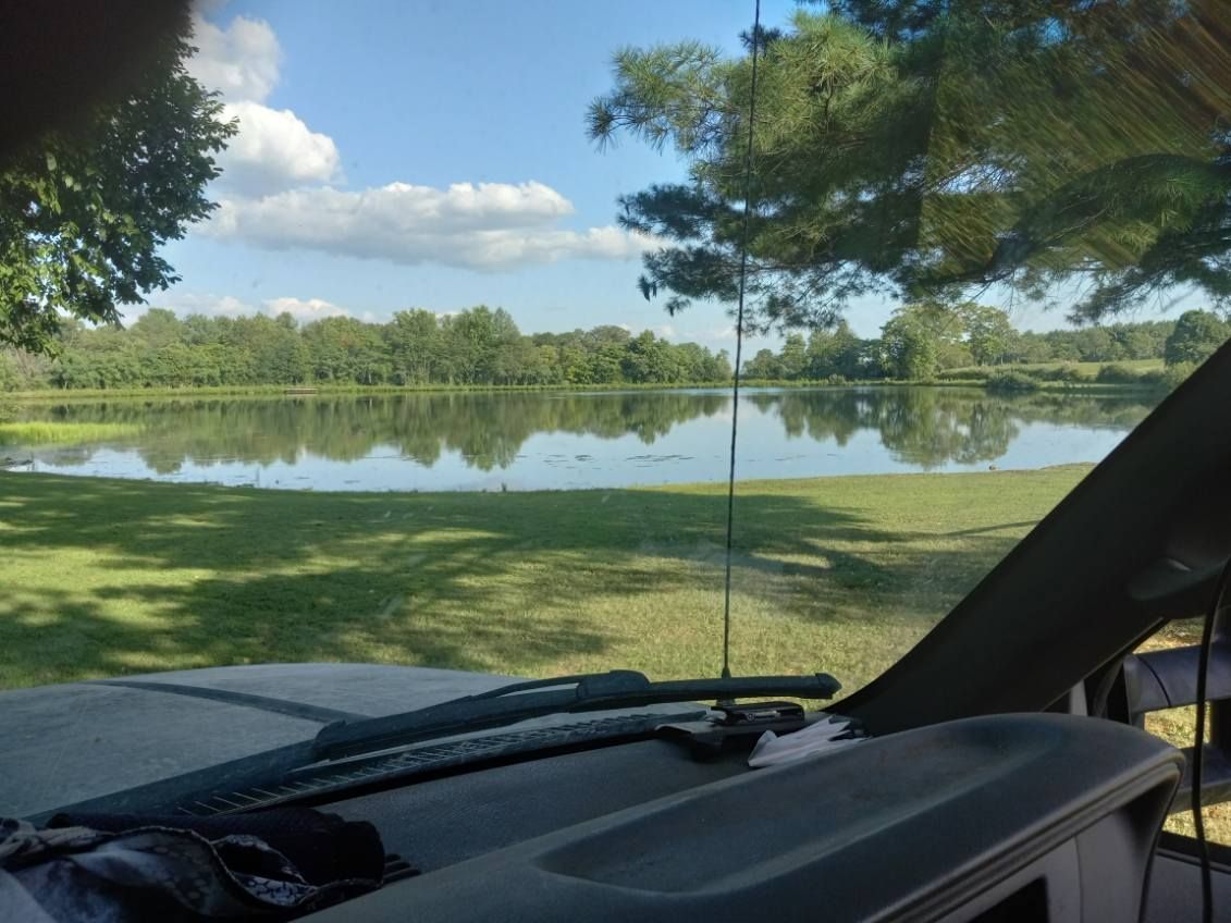A view of a lake through the windshield of a car.