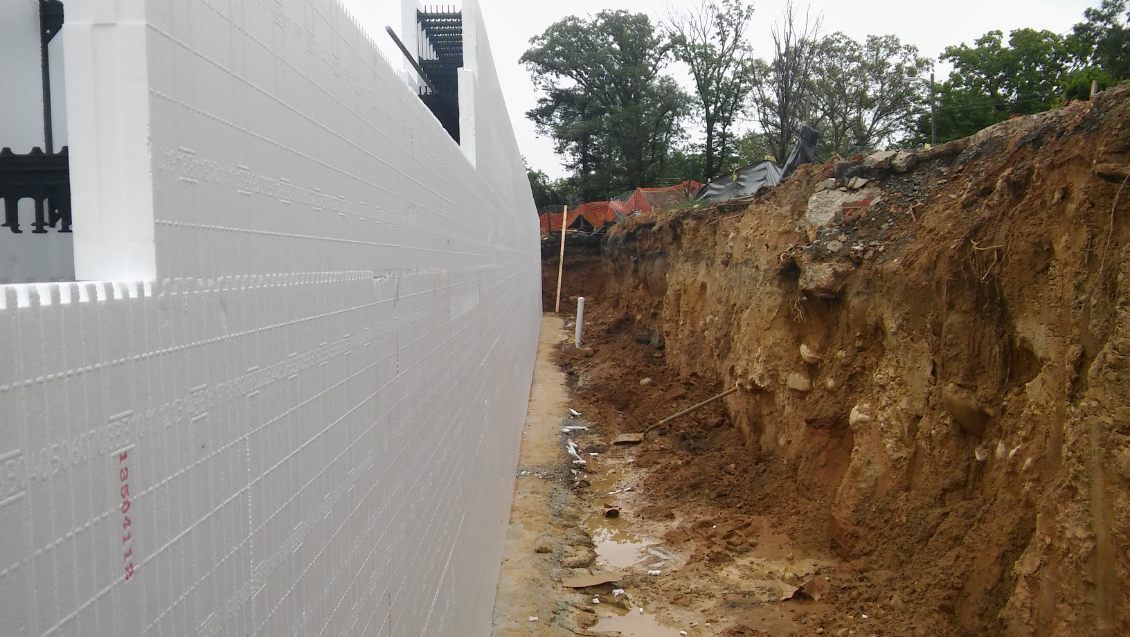A white wall is being built next to a large pile of dirt.